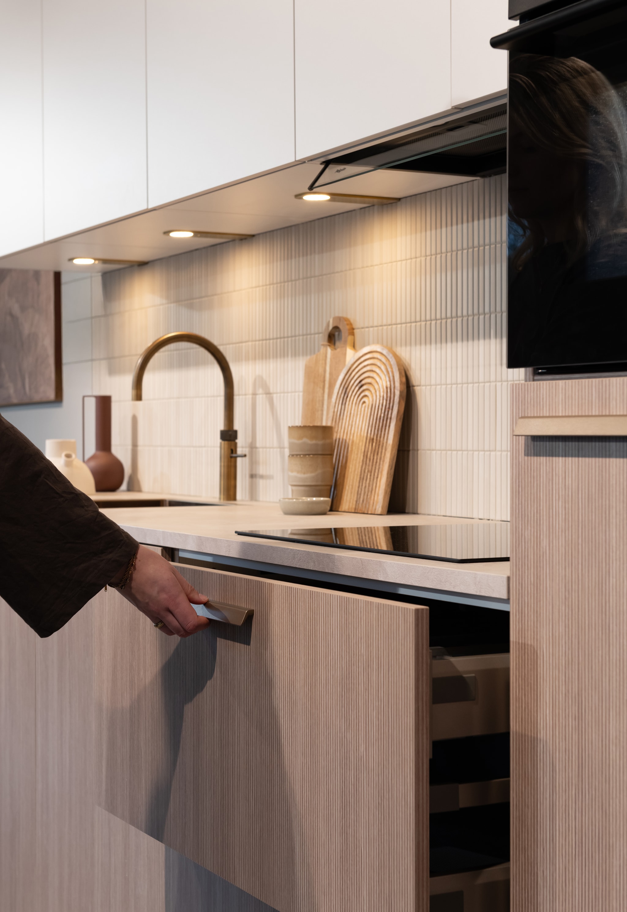 Lichte houten keukenfronten, een messing kraan en een open lade.